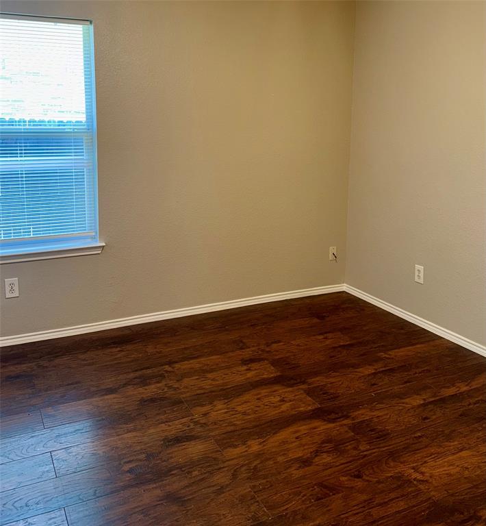 805 Gillon Drive Arlington, TX 76001 - Photo 7 of 12 a view of an empty room with wooden floor and a window