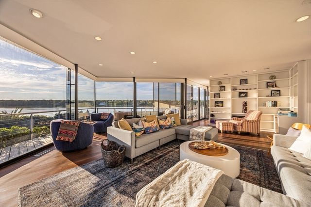 a living room with furniture large windows and wooden floor