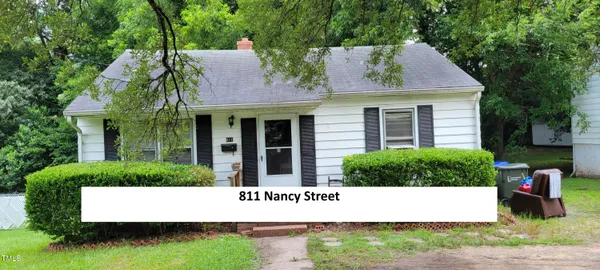 a view of a white house with a small yard and a large tree