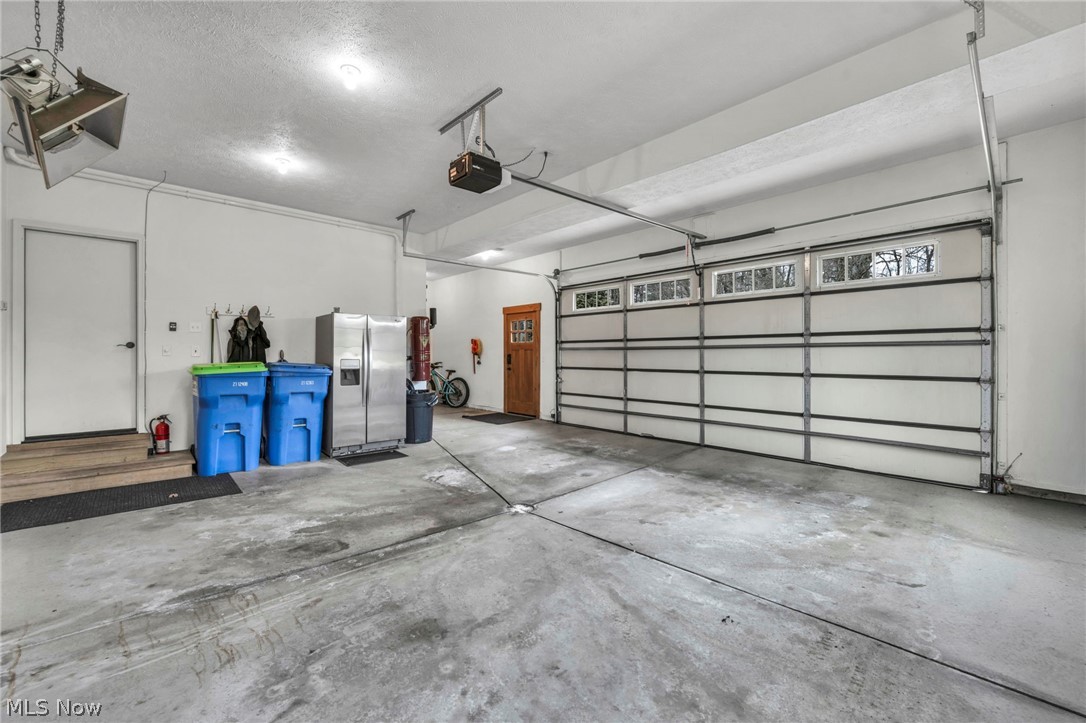 11295 Sutton Place Chardon, OH 44024 - Photo 44 of 50 Garage featuring stainless steel fridge with ice dispenser and a garage door opener
