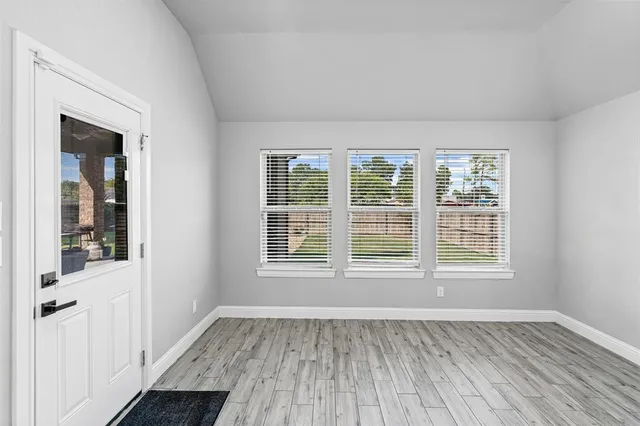 an empty room with wooden floor and windows