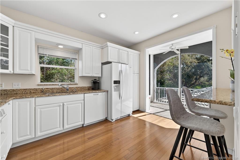 12400 Harbour Ridge Boulevard, Unit 58 Palm City, FL 34990 - Photo 16 of 42 a kitchen with granite countertop a stove a refrigerator a sink a dining table and chairs