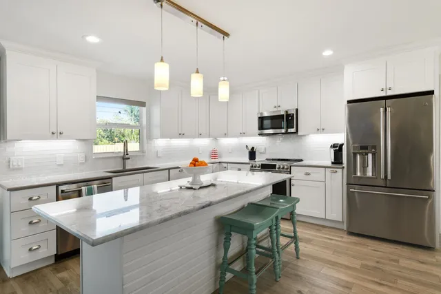 a kitchen with a refrigerator a microwave a sink and wooden floor