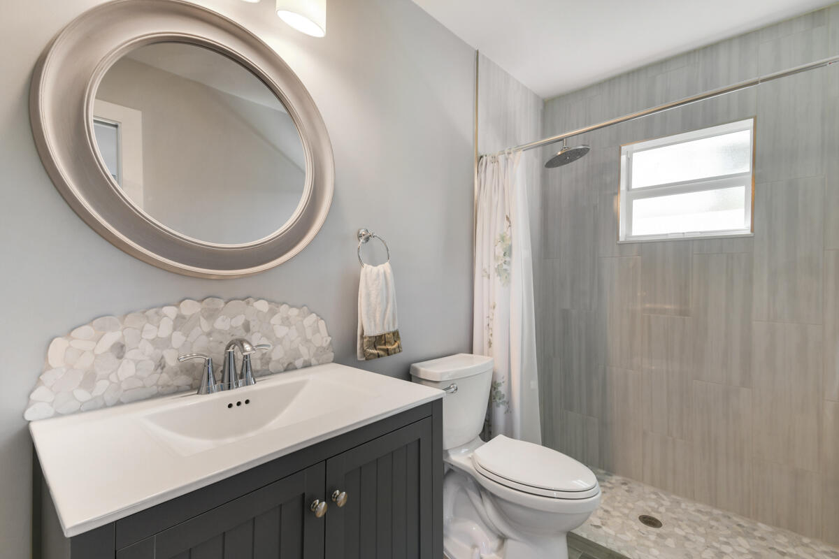 4835 Bimini Road Jupiter, FL 33469 - Photo 30 of 37 a bathroom with a toilet a sink and a mirror