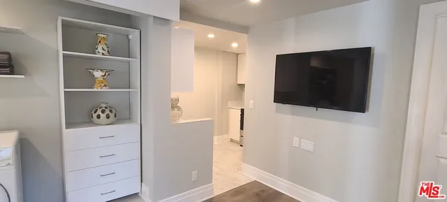 a view of hallway with wooden floor and cabinet