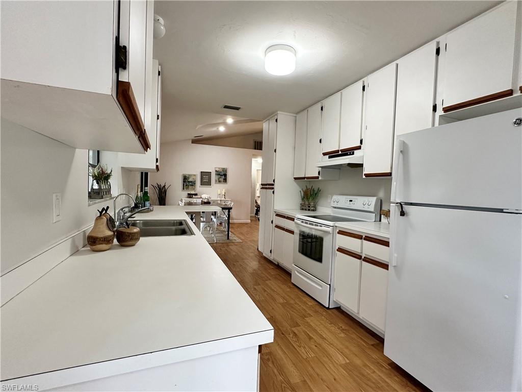 1961 Krape Road Naples, FL 34120 - Photo 27 of 44 a kitchen with stainless steel appliances a sink a stove a refrigerator cabinets and a wooden floor