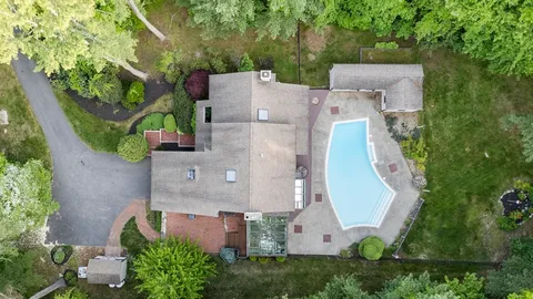 an aerial view of a house with a yard and a large tree