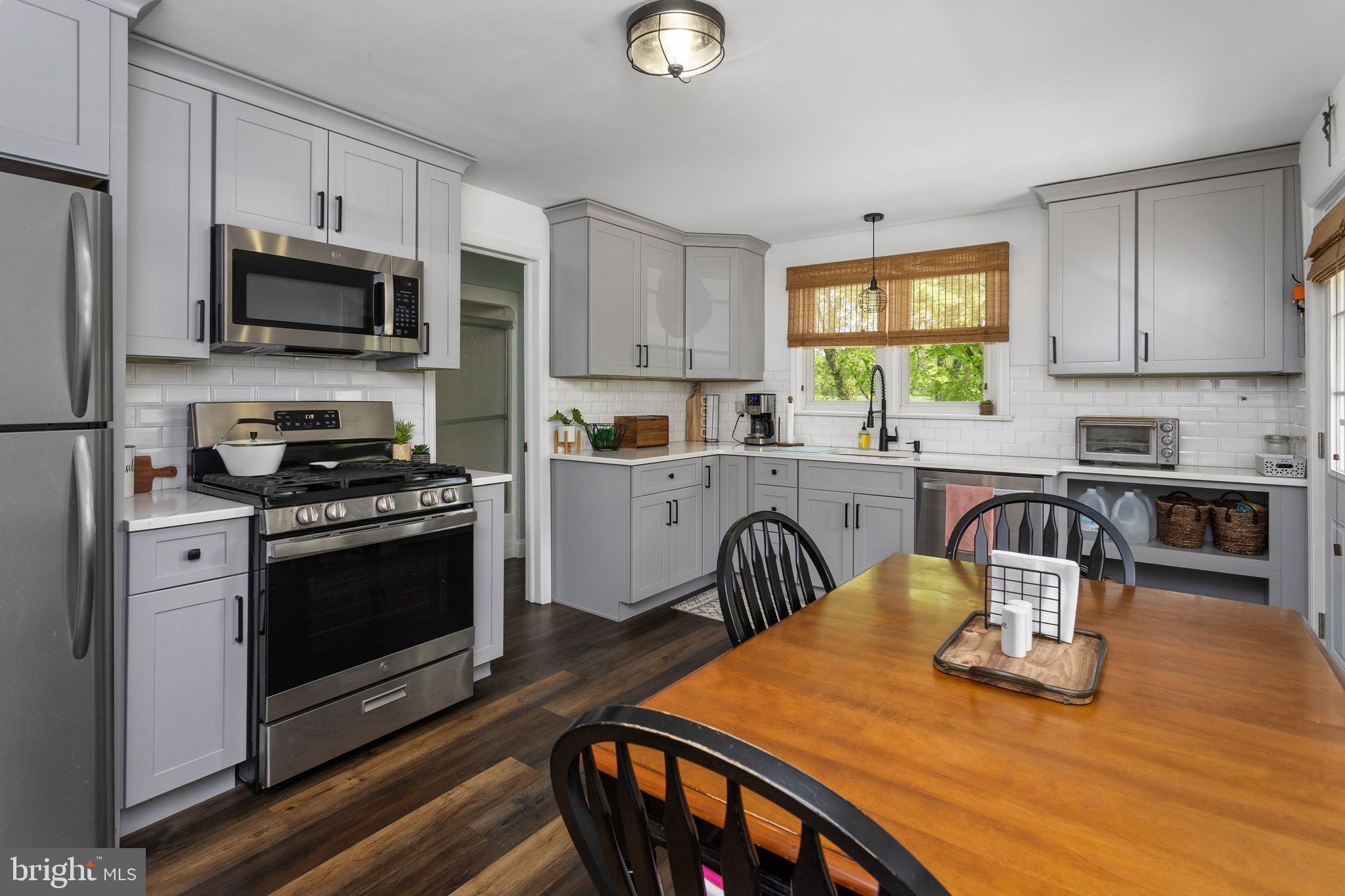 3950 Crosswicks Hamilton Square Road Hamilton, NJ 08691 - Photo 16 of 41 a kitchen with stainless steel appliances granite countertop a stove top oven a sink dishwasher a dining table and chairs with wooden floor