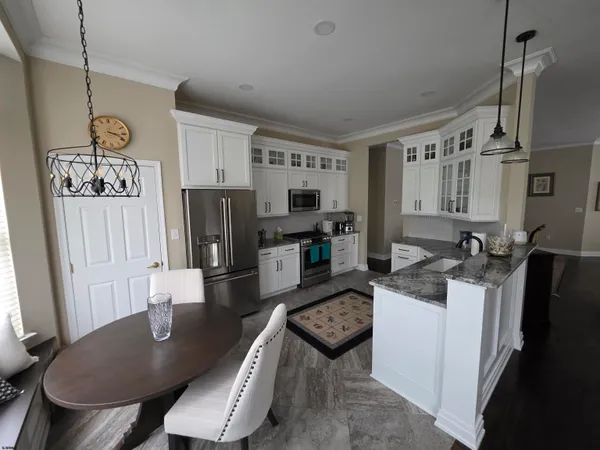 a kitchen with stainless steel appliances granite countertop a stove a refrigerator a sink a dining table and chairs with wooden floor