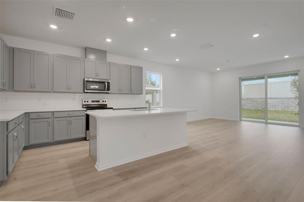 2878 Supermarine Road Tavares, FL 32778 - Photo 15 of 23 a kitchen with kitchen island granite countertop white cabinets and stainless steel appliances