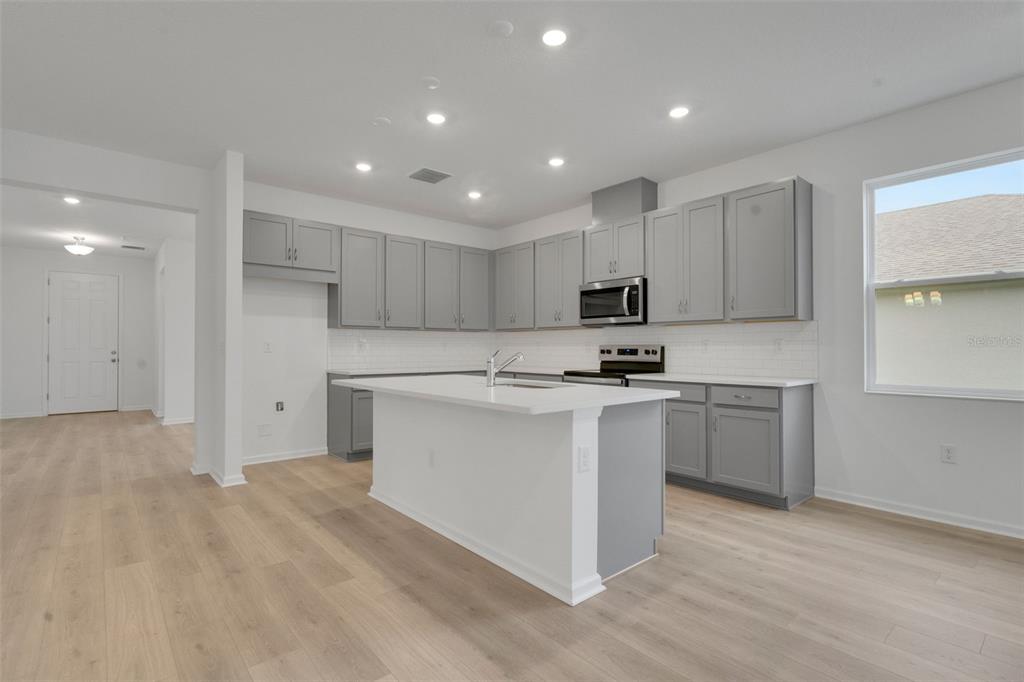 2878 Supermarine Road Tavares, FL 32778 - Photo 16 of 23 a kitchen with stainless steel appliances granite countertop a stove a sink and a refrigerator with wooden floor