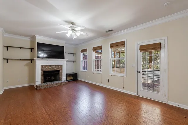 a view of a livingroom with a fireplace a ceiling fan and windows