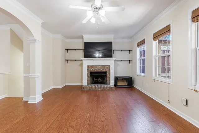 a view of an empty room with wooden floor fireplace and a window