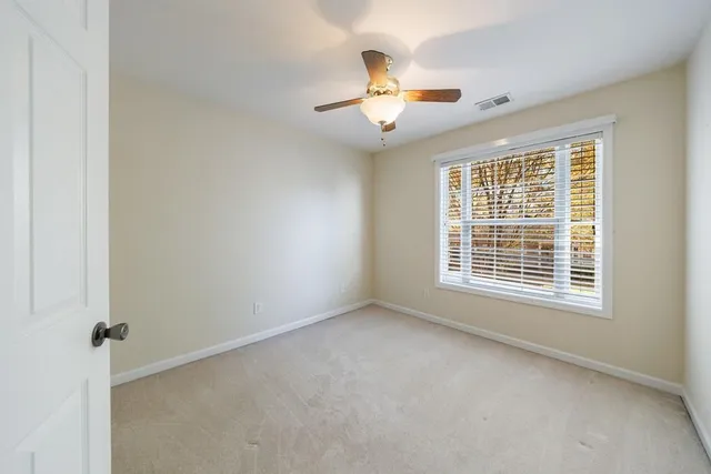 an empty room with a chandelier fan and windows