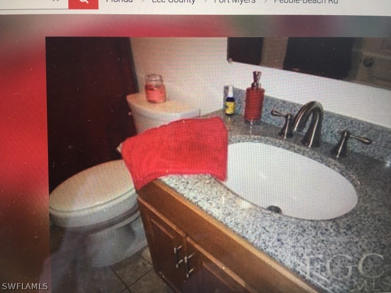 7489 Pebble Beach Road Fort Myers, FL 33967 - Photo 4 of 7 a bathroom with a granite countertop toilet and a sink