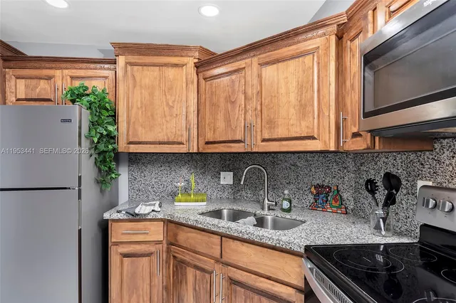 a kitchen with stainless steel appliances granite countertop a sink a refrigerator and cabinets
