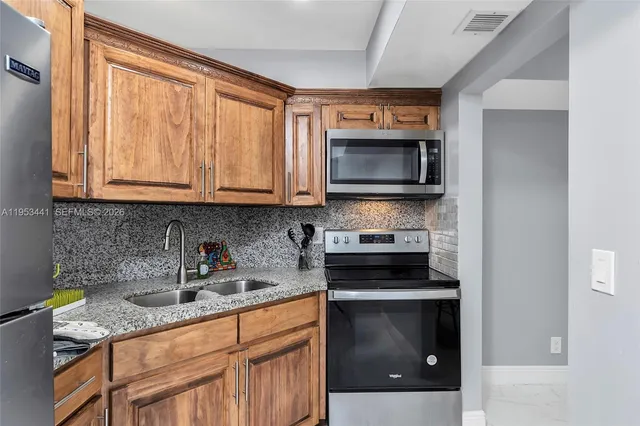 a kitchen with stainless steel appliances granite countertop a stove a microwave and a sink