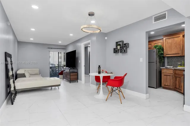 a living room with furniture a flat screen tv and kitchen view