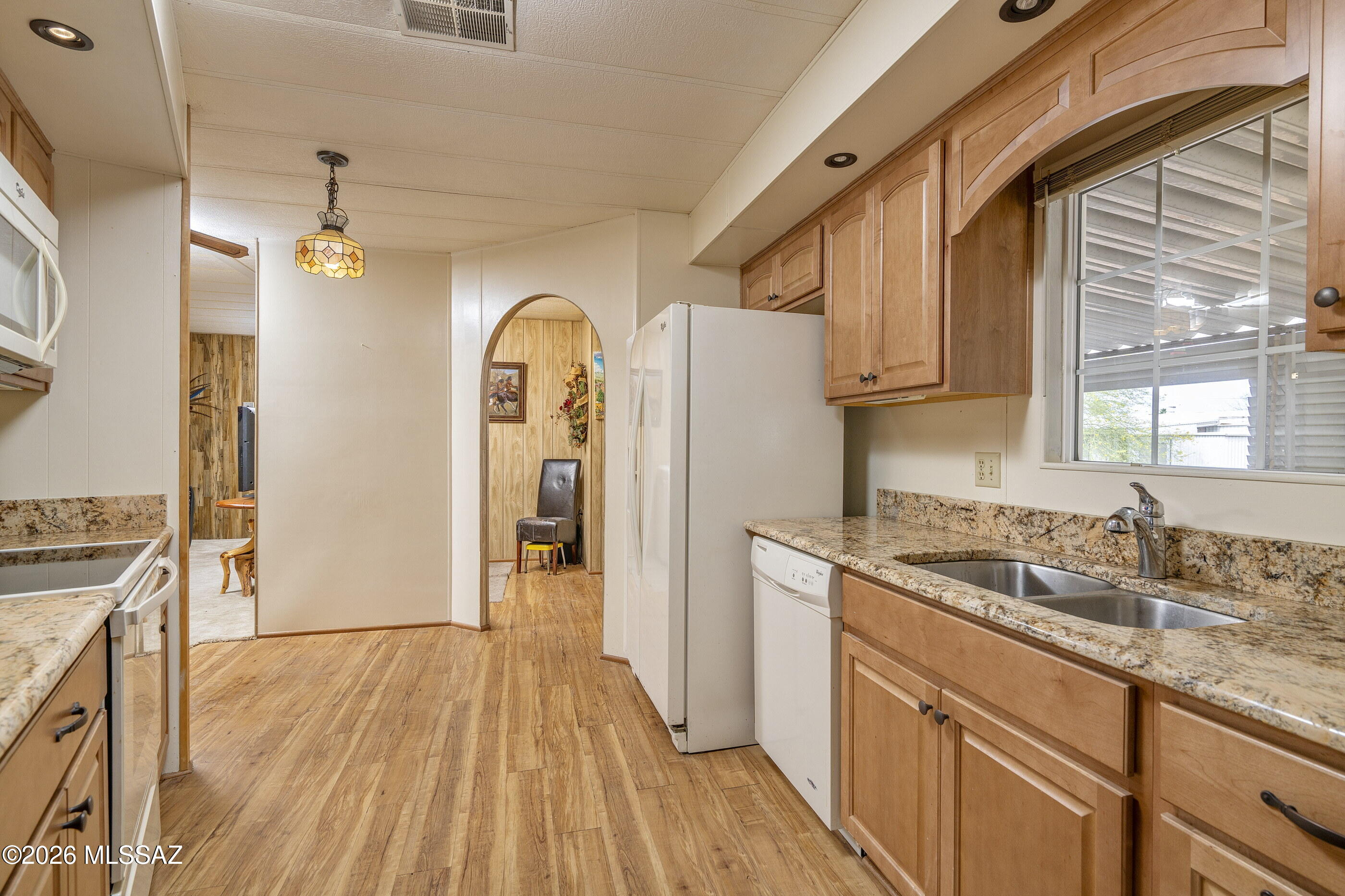 6121 West Flying M Street Tucson, AZ 85713 - Photo 5 of 25 a kitchen with granite countertop a refrigerator a sink dishwasher a stove and white cabinets with wooden floor