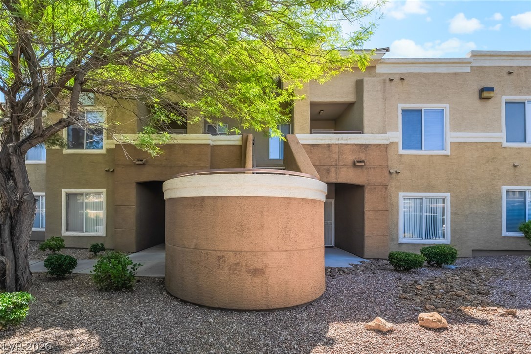 8070 West Russell Road, Unit 2024 Las Vegas, NV 89113 - Photo 2 of 19 A well-maintained multi-level building features a harmonious blend of brown and tan stucco, complemented by lush greenery and a gravel landscape.