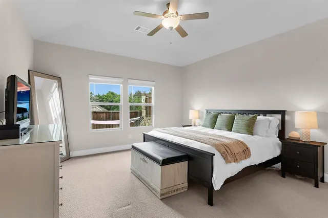 a spacious bedroom with a bed a window and flat screen tv
