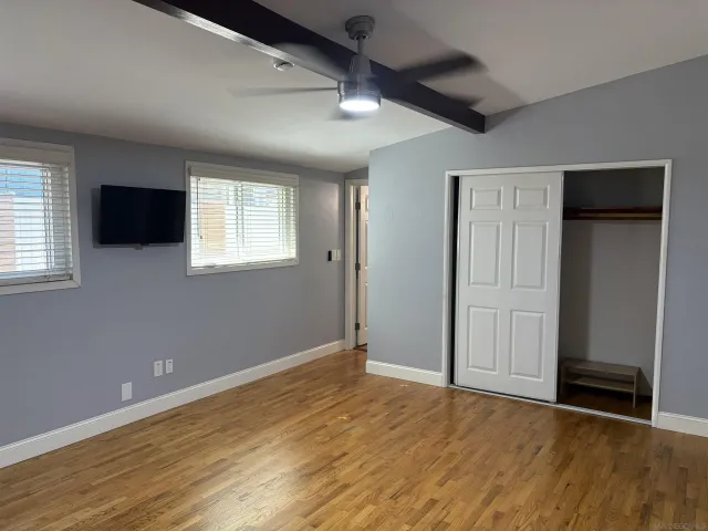 an empty room with wooden floor and windows