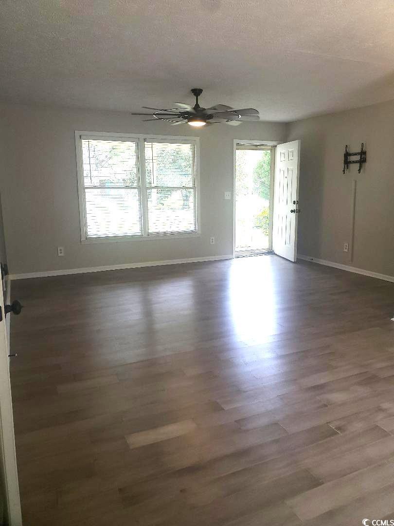 615 Burcale Rd Circle Myrtle Beach, SC 29579 - Photo 3 of 17 Unfurnished room with wood finished floors, a ceiling fan, baseboards, and a textured ceiling