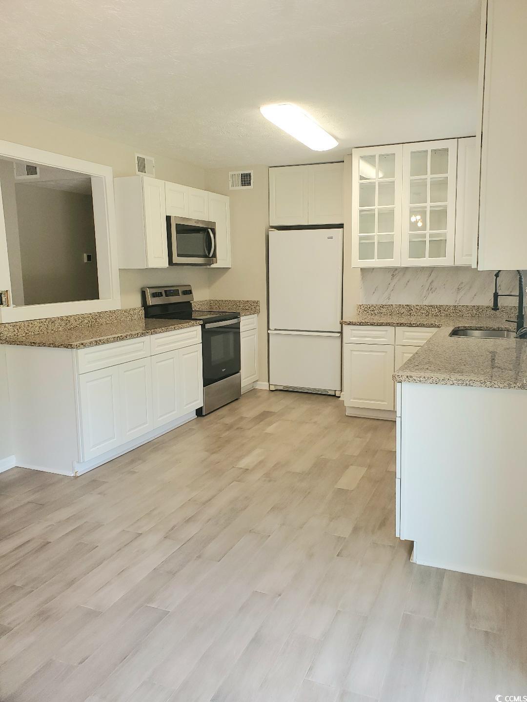 615 Burcale Rd Circle Myrtle Beach, SC 29579 - Photo 5 of 17 Kitchen featuring visible vents, a sink, light stone countertops, appliances with stainless steel finishes, and white cabinetry