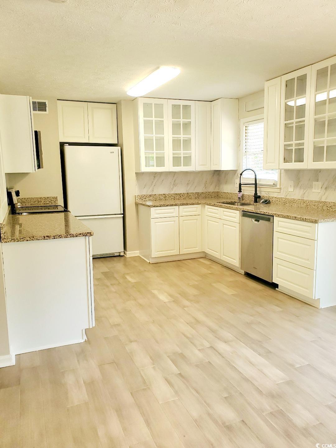 615 Burcale Rd Circle Myrtle Beach, SC 29579 - Photo 6 of 17 Kitchen with light stone counters, visible vents, stainless steel dishwasher, a sink, and freestanding refrigerator
