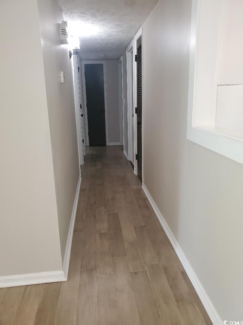 615 Burcale Rd Circle Myrtle Beach, SC 29579 - Photo 10 of 17 Hall with baseboards, light wood-style floors, and a textured ceiling