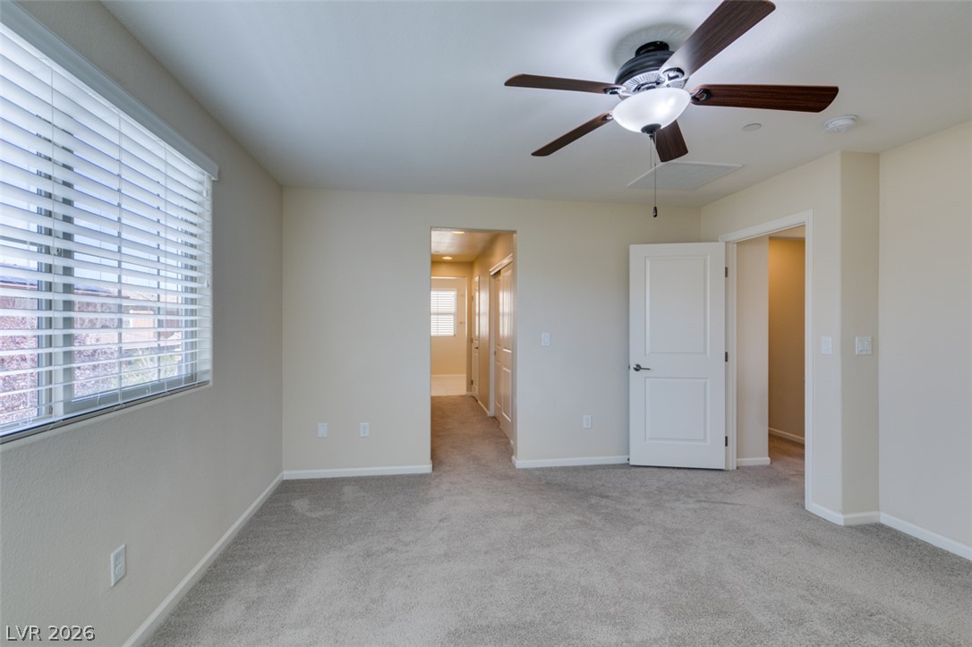 2549 Sable Ridge Street Henderson, NV 89044 - Photo 43 of 48 A quiet bedroom featuring plush carpeting, a large window, and a modern ceiling fan for comfort.