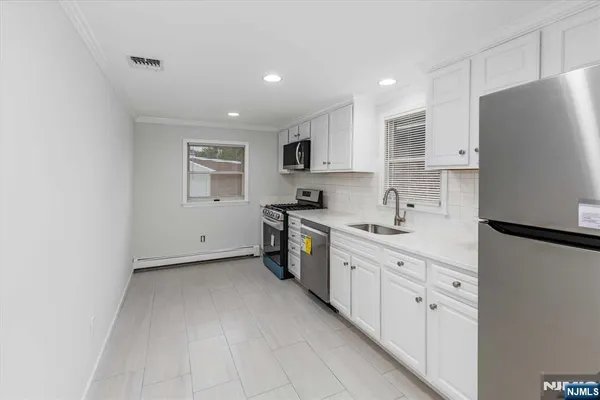 a kitchen with stainless steel appliances a refrigerator sink and white cabinets