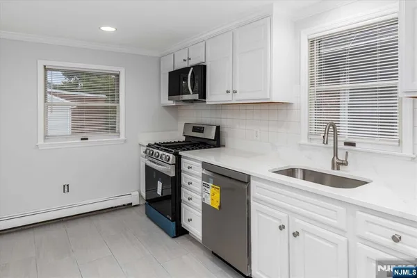 a kitchen with granite countertop white cabinets and stainless steel appliances
