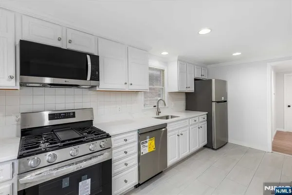 a kitchen with stainless steel appliances a stove a microwave a sink and cabinets