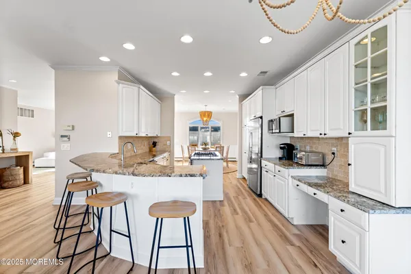 a kitchen with stainless steel appliances granite countertop a table chairs sink and cabinets