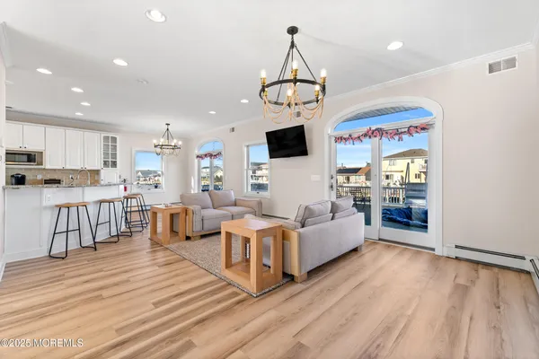 a living room with couches a dining table and kitchen view with wooden floor