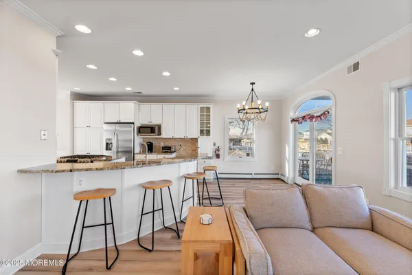 a living room with stainless steel appliances furniture and a kitchen view