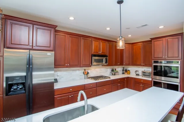 a kitchen with stainless steel appliances a sink a stove a refrigerator cabinets and a kitchen island