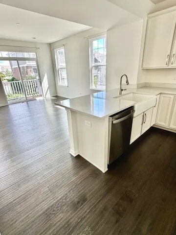 a kitchen with stainless steel appliances granite countertop a sink a stove and wooden floors