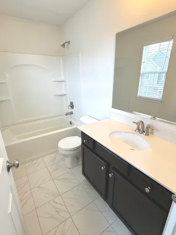 a bathroom with a granite countertop sink toilet mirror vanity and bathtub