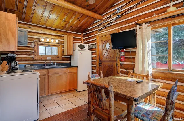 a open kitchen with stainless steel appliances granite countertop a stove top oven a sink dishwasher a dining table and chairs with wooden floor