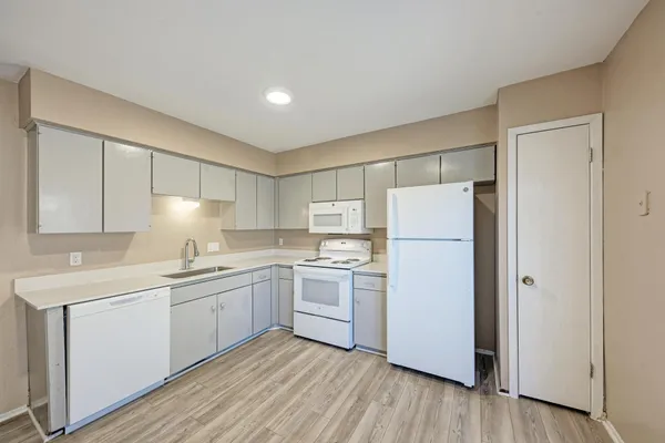 a kitchen with a sink a refrigerator and white cabinets