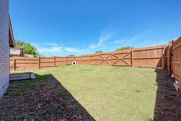 a view of a yard with wooden fence