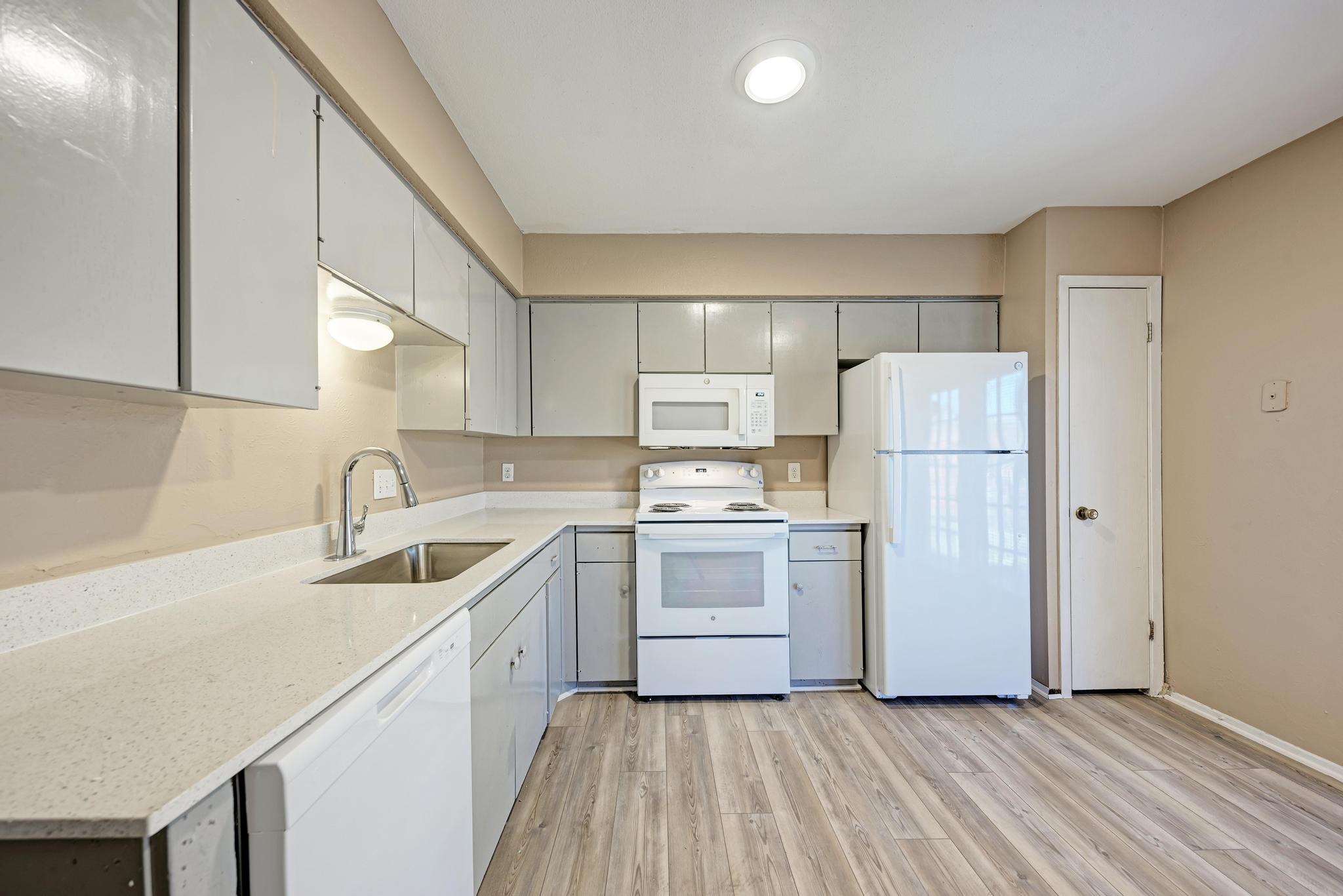 1117 West Rundberg Lane, Unit A Austin, TX 78758 - Photo 10 of 31 Kitchen with white appliances, light wood-type flooring, light stone countertops, and gray cabinetry