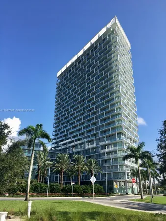 a view of a tall building with a big yard and palm trees
