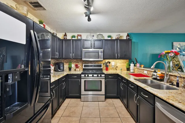 a kitchen with stainless steel appliances granite countertop a stove sink and cabinets