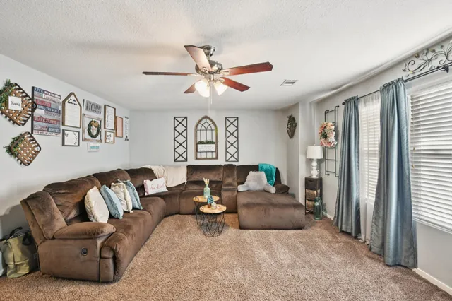 a living room with furniture ceiling fan and a window