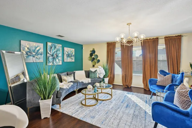a living room with furniture kitchen view and a wooden floor