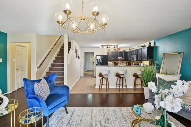 a living room with lots of furniture kitchen view and a chandelier