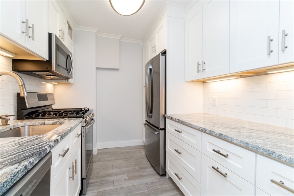33 Pond Avenue, Unit 1106 Brookline, MA 02445 - Photo 9 of 32 a kitchen with stainless steel appliances granite countertop a refrigerator a stove and a sink with wooden floors